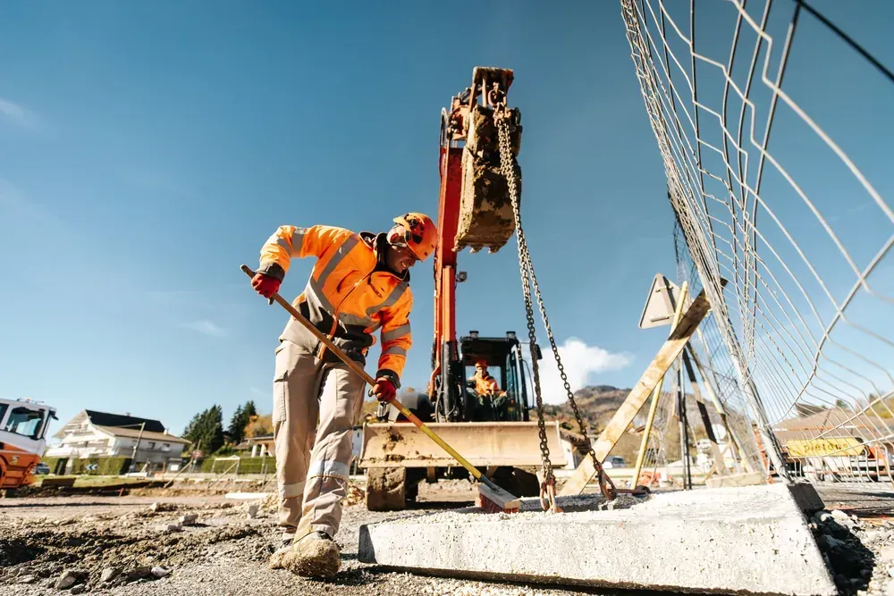 Compagnon guidant une pelle mécanique sur un chantier de VRD